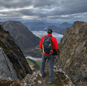 A mountain climber stands on a mountain peak and looks down into a valley.