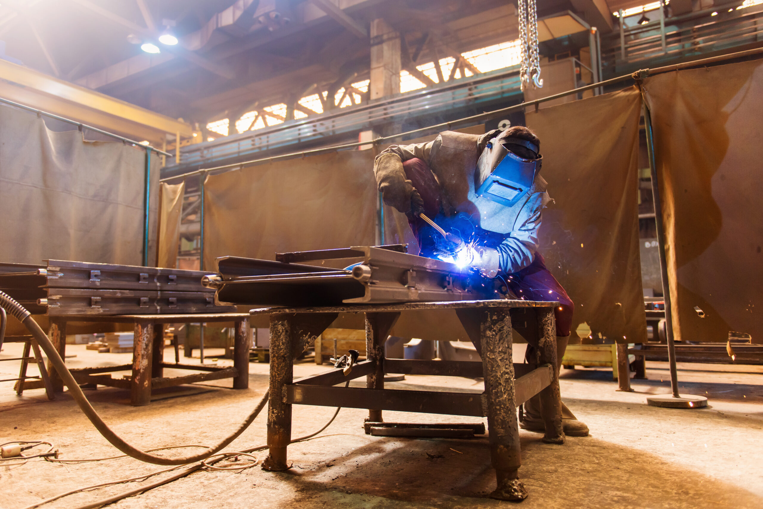 Young man with protective mask welding in a factory,
