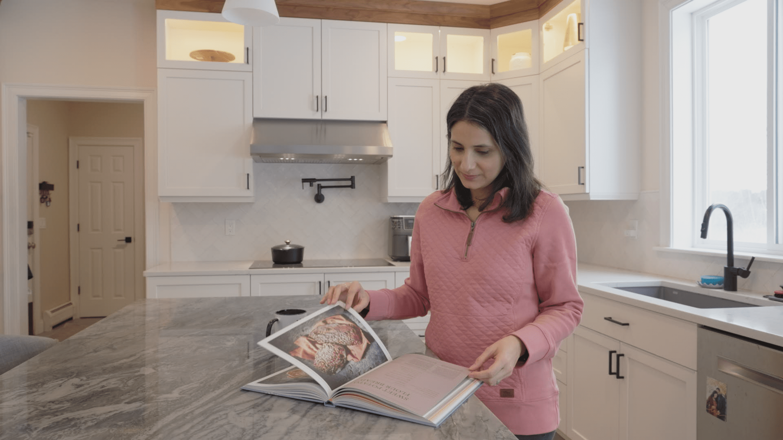Woman reading cook book on kitchen island